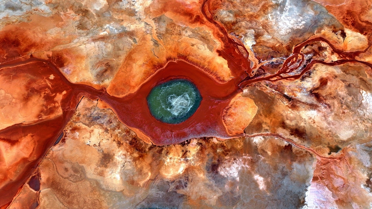 A vivid red spring forms an eye-like pattern in the earth.