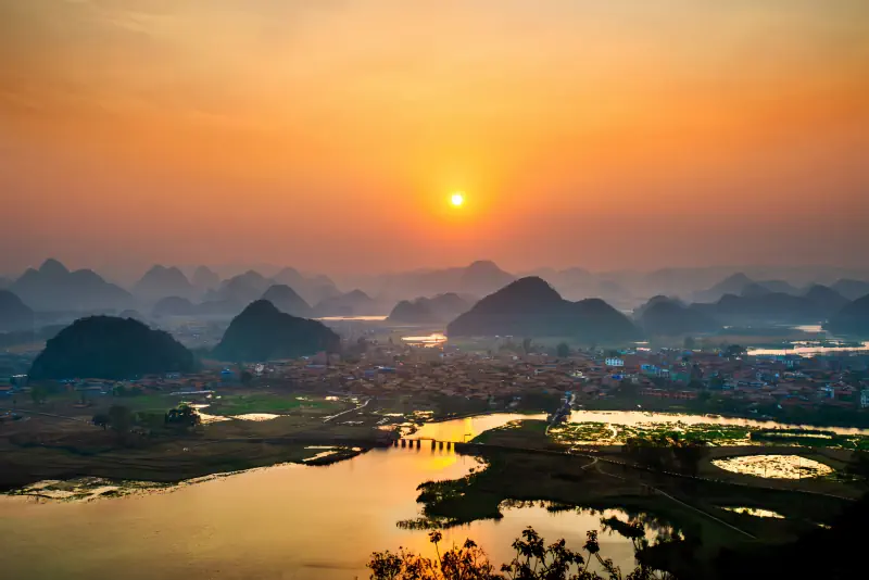 Sunrise glows over the lakes and hills of Puzhehei.