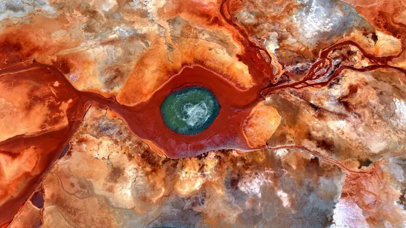 A vivid red spring forms an eye-like pattern in the earth.
